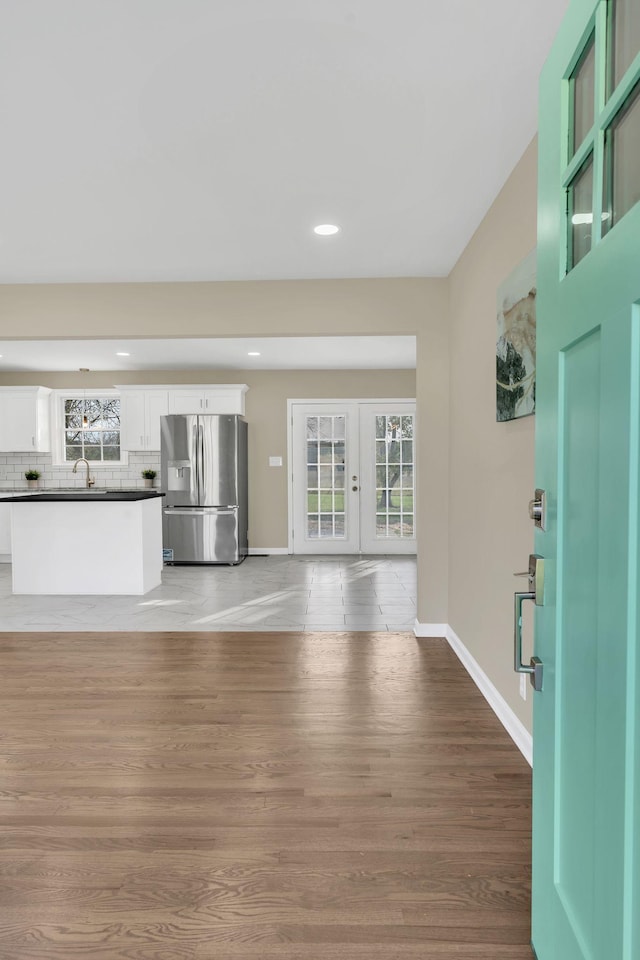 unfurnished living room featuring sink, french doors, and light wood-type flooring