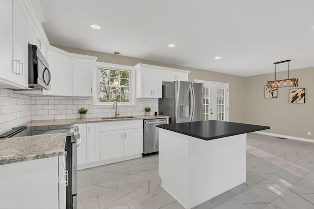 kitchen featuring a kitchen island, appliances with stainless steel finishes, pendant lighting, sink, and white cabinets