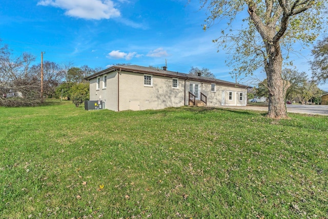 rear view of house with cooling unit and a lawn