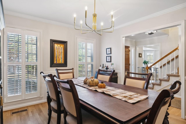 dining area featuring a notable chandelier, ornamental molding, and light wood-type flooring