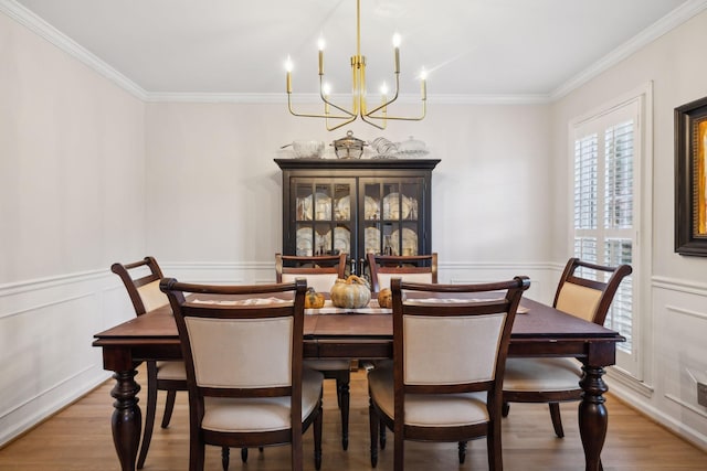 dining area with wood-type flooring, ornamental molding, and a chandelier