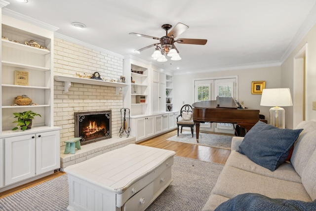 living room with crown molding, ceiling fan, a brick fireplace, and light wood-type flooring