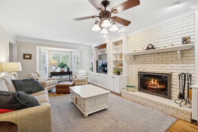 living room with crown molding, a brick fireplace, ceiling fan, and light hardwood / wood-style flooring