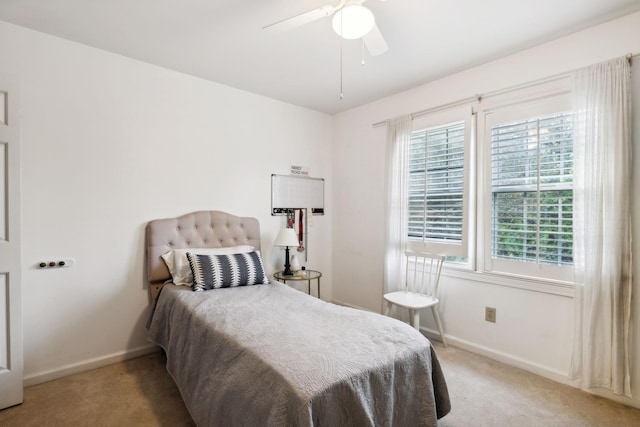 bedroom with ceiling fan, light colored carpet, and multiple windows