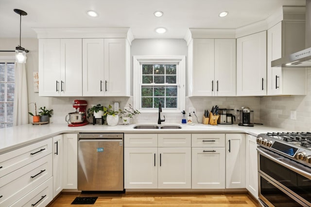 kitchen featuring white cabinetry, sink, wall chimney range hood, and stainless steel appliances