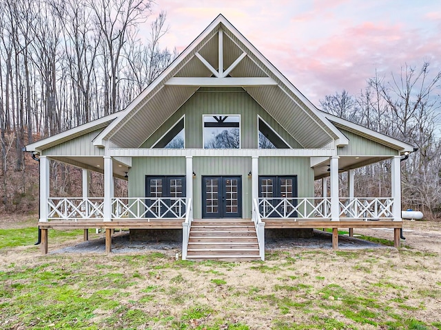 back house at dusk with french doors and covered porch