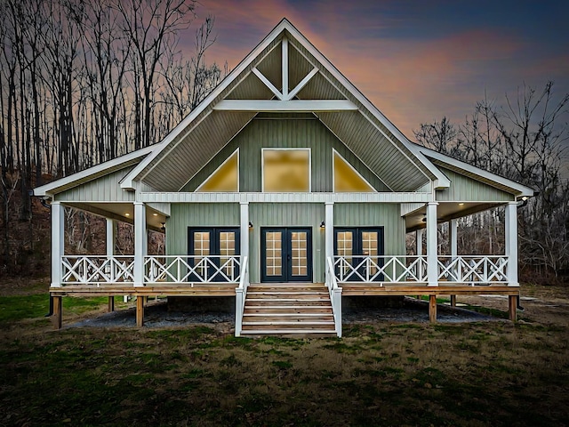 back house at dusk with french doors and covered porch