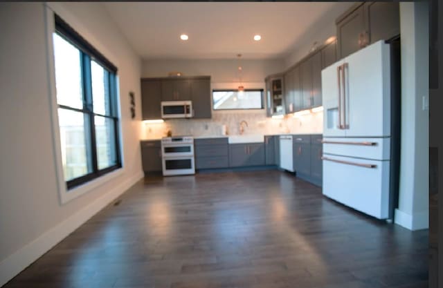 kitchen featuring white appliances, dark hardwood / wood-style floors, gray cabinets, and decorative backsplash