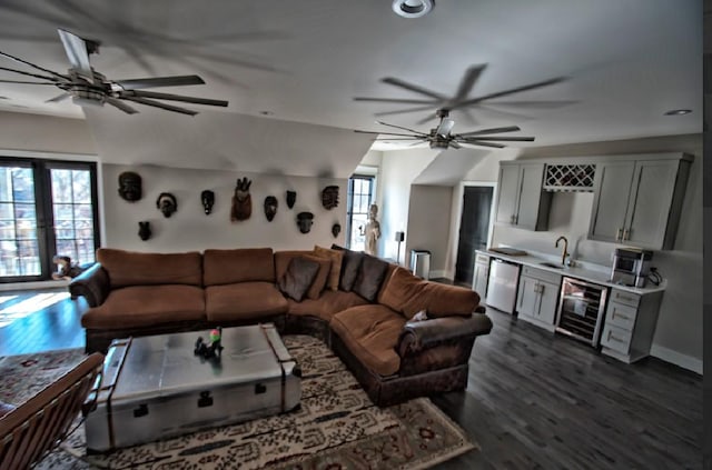 living room featuring dark wood-type flooring, beverage cooler, vaulted ceiling, and wet bar