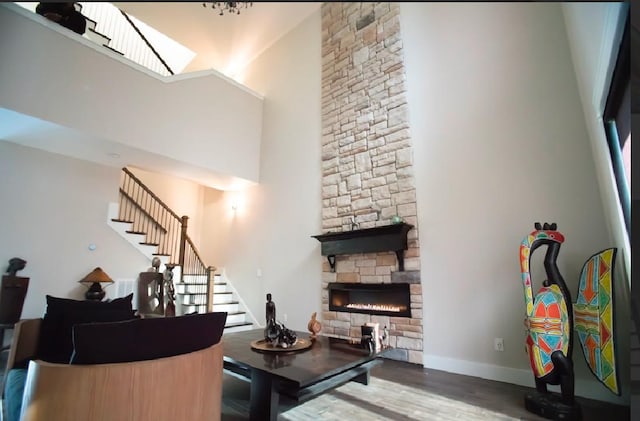 living room featuring hardwood / wood-style flooring, a fireplace, and a high ceiling