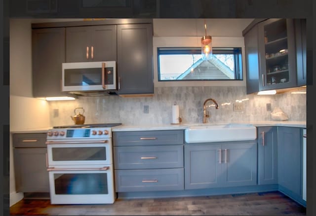 kitchen featuring tasteful backsplash, dark hardwood / wood-style flooring, sink, and range with two ovens