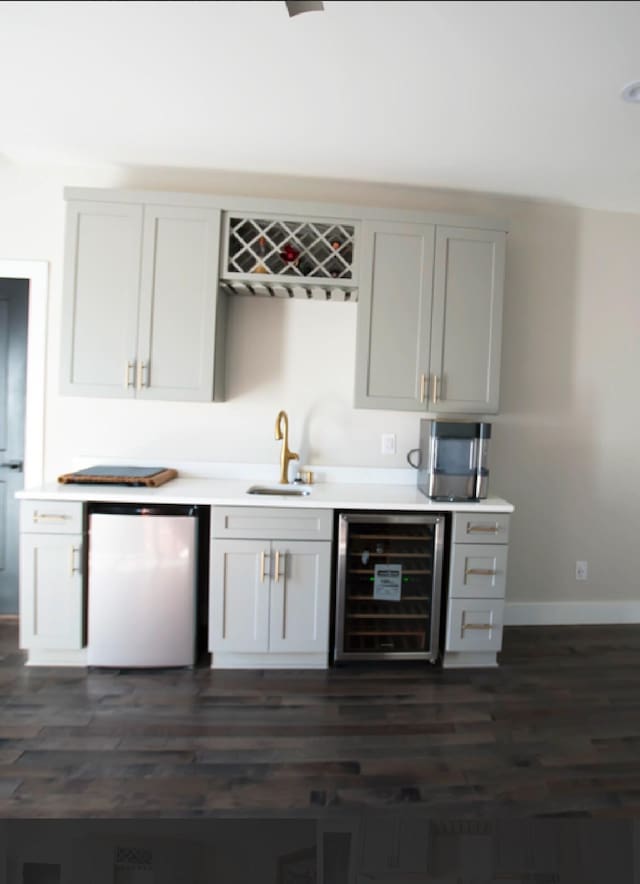 bar featuring fridge, beverage cooler, sink, and white cabinets