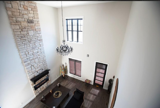 living room with a stone fireplace, dark wood-type flooring, and a chandelier