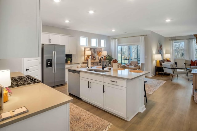 kitchen with sink, appliances with stainless steel finishes, a kitchen island with sink, white cabinetry, and plenty of natural light