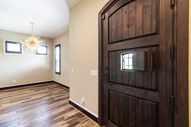 entrance foyer featuring plenty of natural light, hardwood / wood-style floors, and a notable chandelier