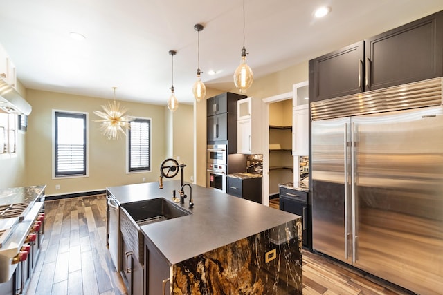 kitchen with hardwood / wood-style flooring, stainless steel appliances, sink, and a center island with sink