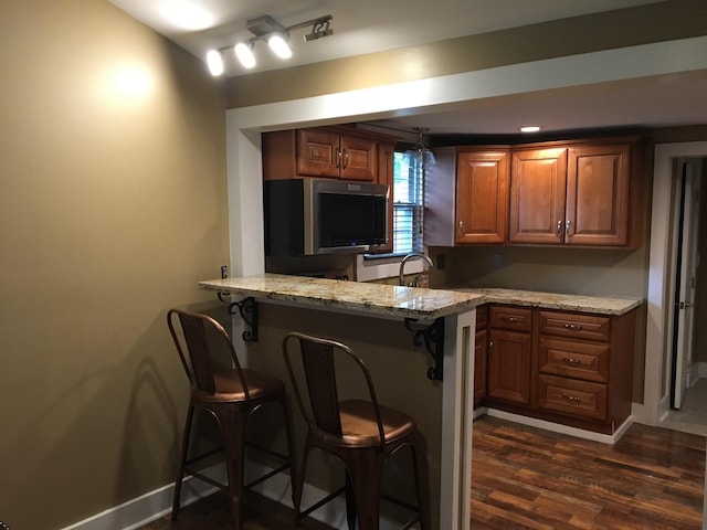 bar featuring dark hardwood / wood-style flooring, sink, and light stone countertops