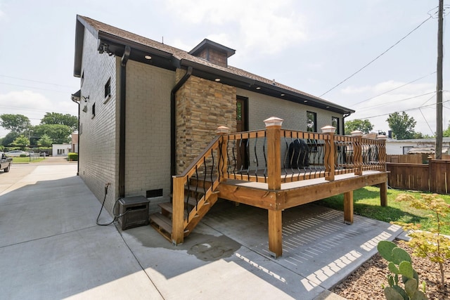 back of property with a wooden deck and a patio