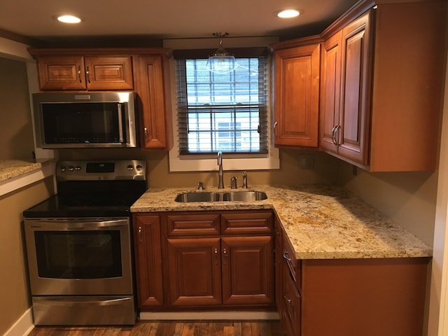 kitchen with light stone counters, stainless steel appliances, sink, and hardwood / wood-style floors