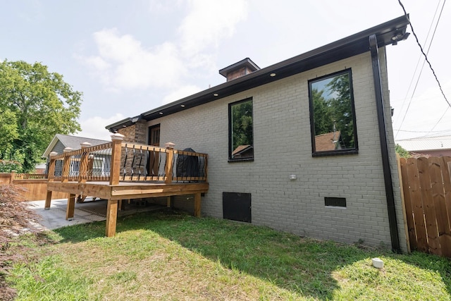 rear view of house featuring a wooden deck and a lawn