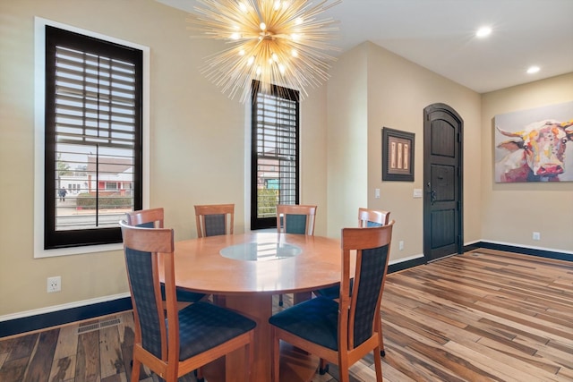 dining space with a notable chandelier, hardwood / wood-style flooring, and a wealth of natural light