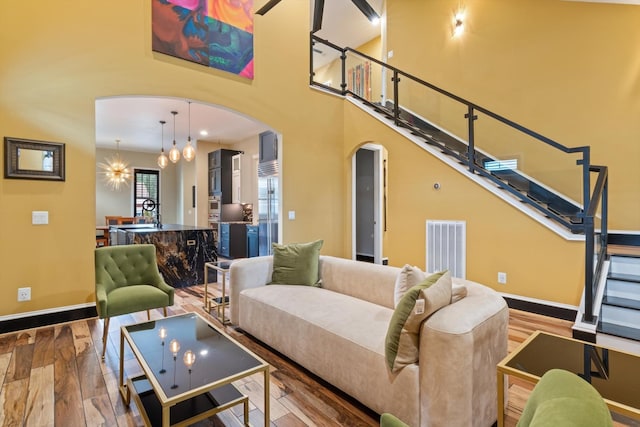 living room with hardwood / wood-style flooring, a chandelier, sink, and a high ceiling