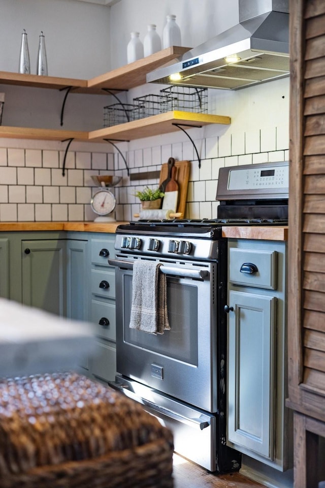 kitchen featuring tasteful backsplash, wall chimney range hood, and gas range