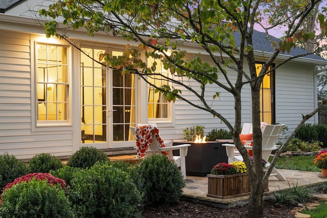 property exterior at dusk featuring french doors, a patio, and an outdoor fire pit