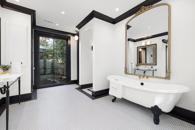 bathroom featuring ornamental molding and a tub to relax in