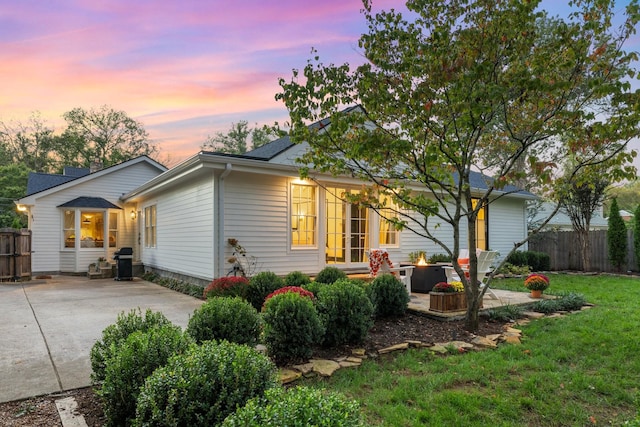 property exterior at dusk with a lawn, a patio area, and an outdoor fire pit