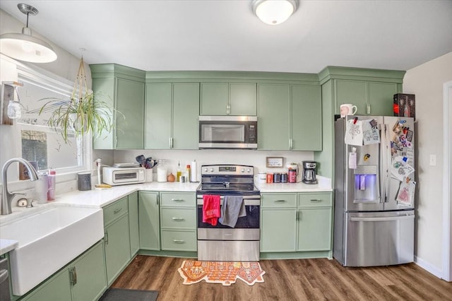 kitchen with dark wood-type flooring, stainless steel appliances, sink, and green cabinets