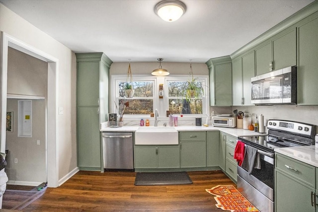 kitchen featuring stainless steel appliances, sink, decorative light fixtures, and green cabinets