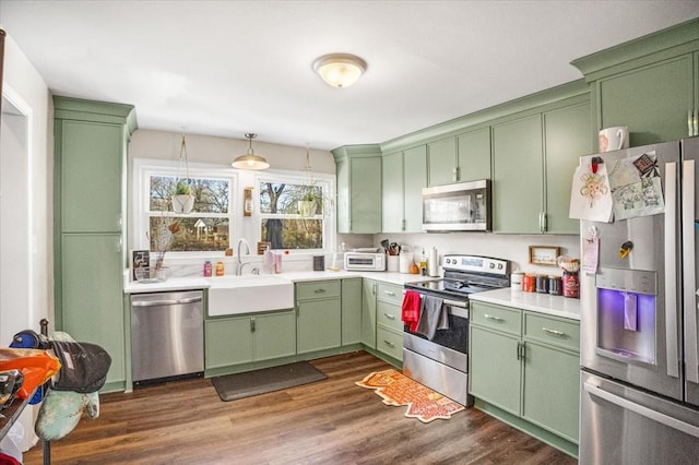 kitchen with dark wood-type flooring, green cabinetry, appliances with stainless steel finishes, and sink