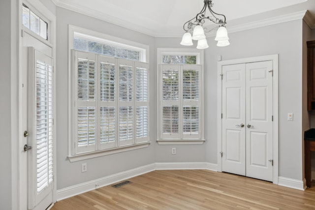 unfurnished dining area with crown molding, an inviting chandelier, and light hardwood / wood-style floors