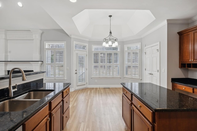 kitchen featuring pendant lighting, sink, dark stone counters, a tray ceiling, and light hardwood / wood-style flooring