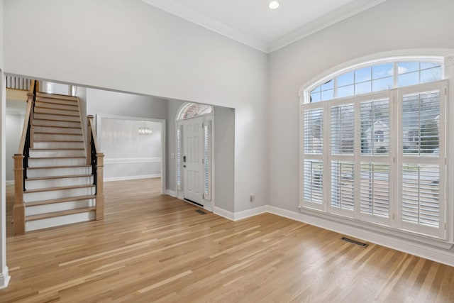 entrance foyer featuring crown molding, a notable chandelier, and light wood-type flooring