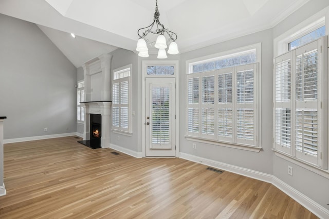 interior space with a wealth of natural light, a chandelier, vaulted ceiling, and light wood-type flooring