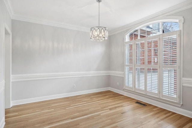 empty room with a notable chandelier, light hardwood / wood-style flooring, and ornamental molding