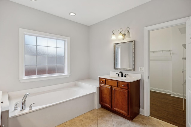 bathroom with tile patterned flooring, vanity, and a bath