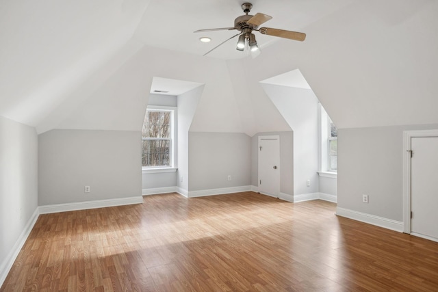 additional living space with hardwood / wood-style flooring, ceiling fan, a healthy amount of sunlight, and lofted ceiling