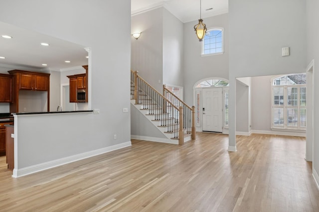 foyer entrance featuring a high ceiling, ornamental molding, and light wood-type flooring