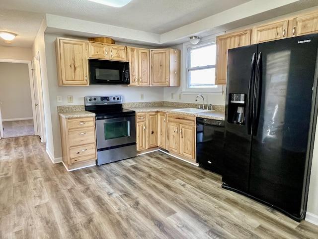 kitchen with sink, black appliances, light hardwood / wood-style floors, a textured ceiling, and light brown cabinets