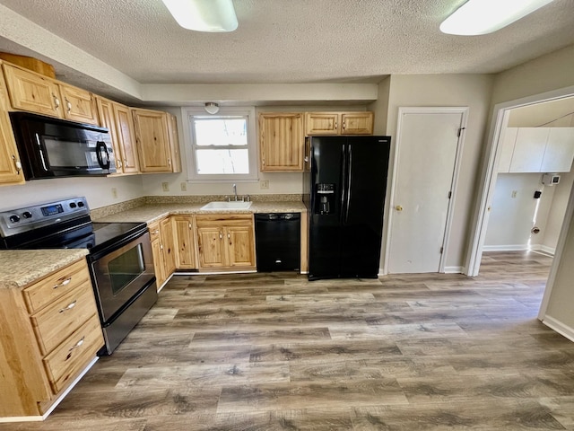 kitchen with light brown cabinets, sink, a textured ceiling, and black appliances