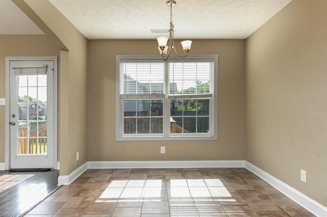 unfurnished dining area with an inviting chandelier and a textured ceiling