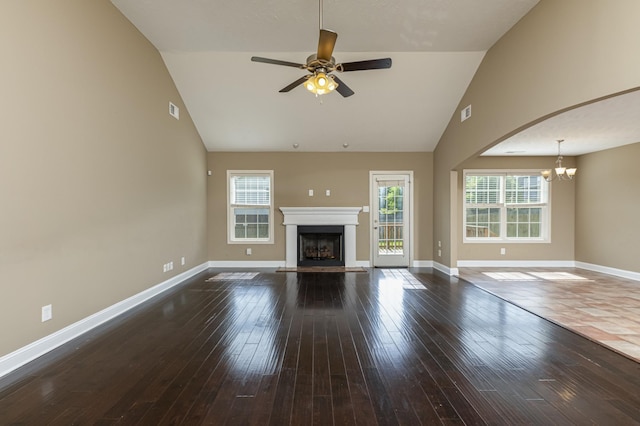 unfurnished living room featuring ceiling fan with notable chandelier, vaulted ceiling, and dark hardwood / wood-style floors