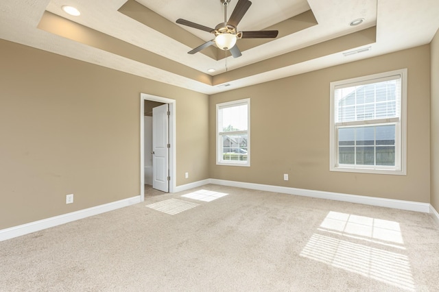 empty room featuring light carpet, ceiling fan, and a tray ceiling