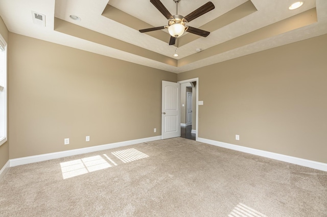 carpeted empty room with ceiling fan and a tray ceiling