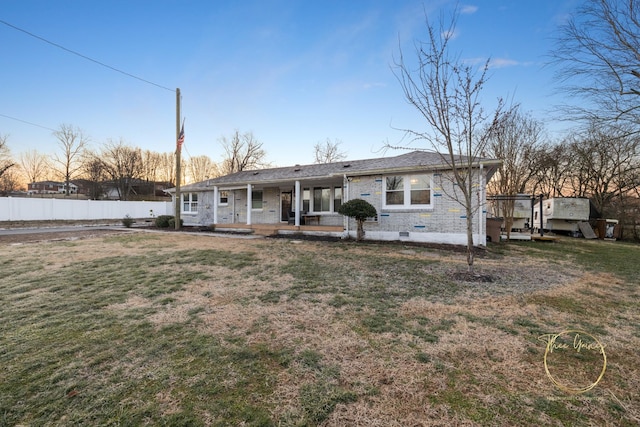 back of house with a lawn, covered porch, brick siding, and fence