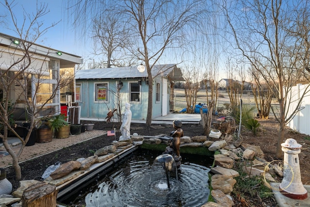 view of yard featuring a garden pond, an outbuilding, and fence