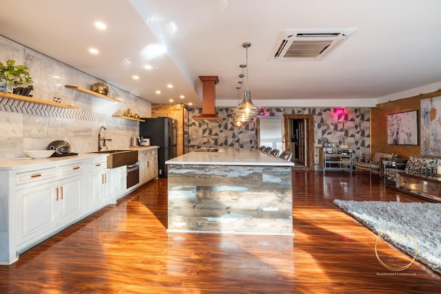 kitchen with wood finished floors, pendant lighting, black fridge with ice dispenser, and a sink